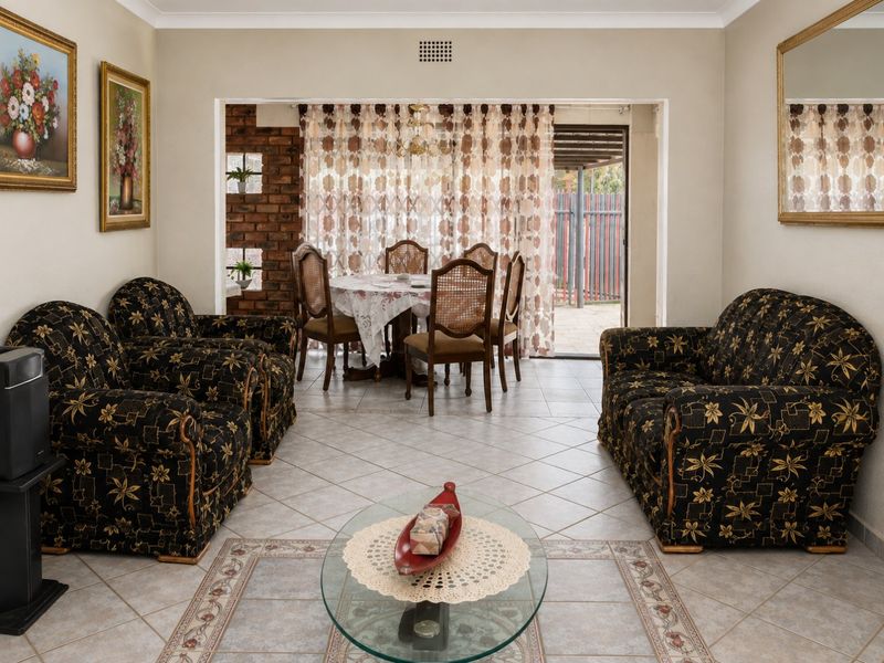 Open-plan living and dining area featuring ceramic tiled flooring, an exposed brick accent wall, and direct access to the outdoor patio through sliding doors.