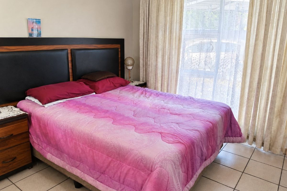 A bedroom featuring tiled flooring and a sliding glass door with curtains, providing natural light and access to the exterior.