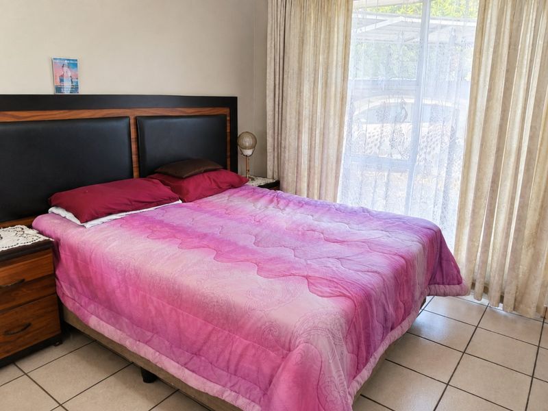 A bedroom featuring tiled flooring and a sliding glass door with curtains, providing natural light and access to the exterior.