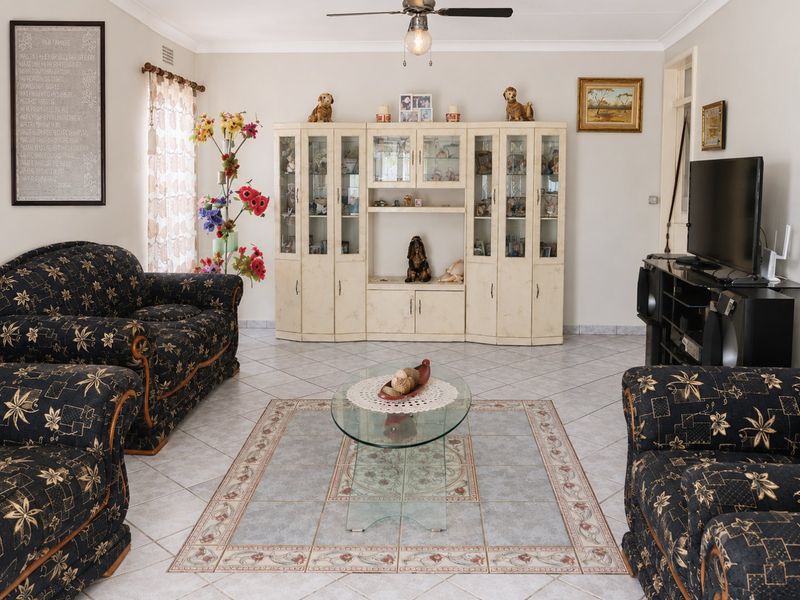 A living room featuring ceramic floor tiles, a ceiling fan, and built-in display cabinetry.