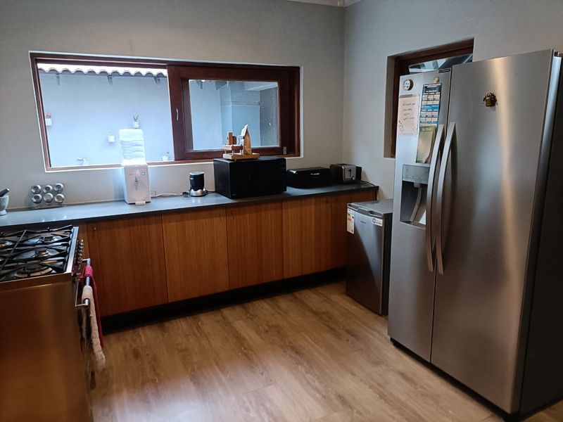 A functional kitchen featuring wood-finish cabinetry, stone countertops, gas stove, and laminate flooring, with a window overlooking an exterior area.
