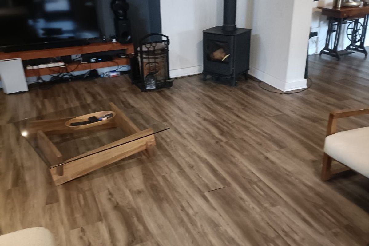 Living room featuring a wood-burning stove, recessed media wall, and wood-look laminate flooring.