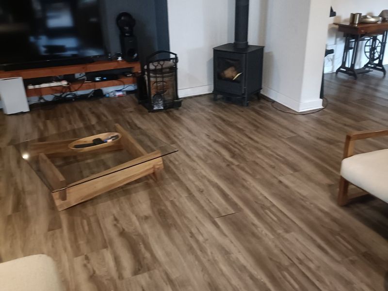 Living room featuring a wood-burning stove, recessed media wall, and wood-look laminate flooring.