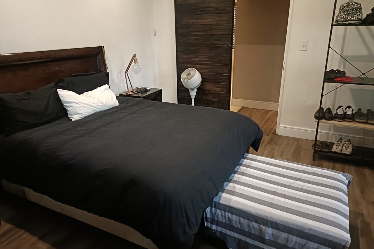 A bedroom featuring dark wood-look laminate flooring and a rustic sliding barn door leading to an adjacent space.