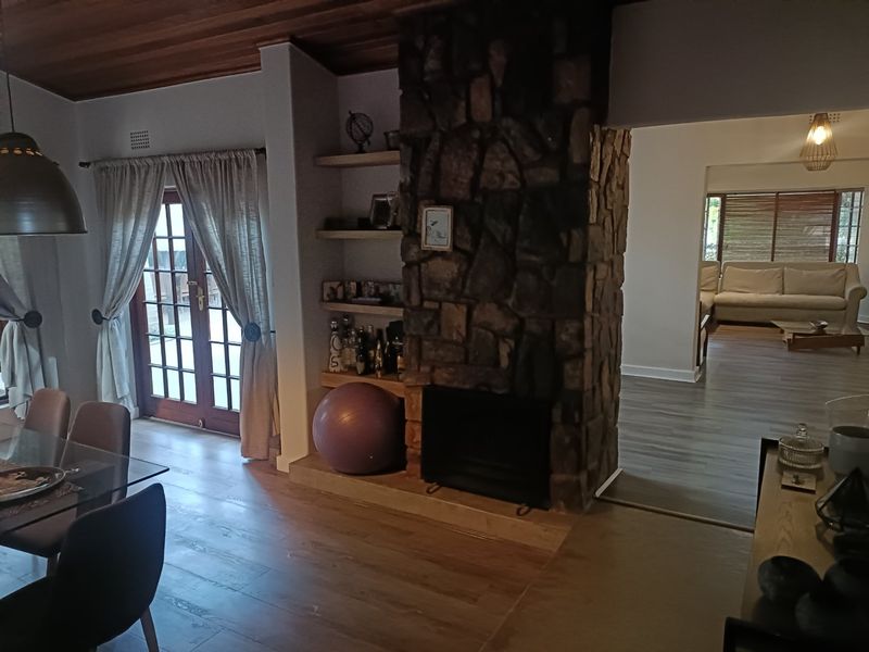 Spacious living area featuring a prominent stone fireplace, timber-clad ceiling, and direct access to the outdoors through classic french doors.