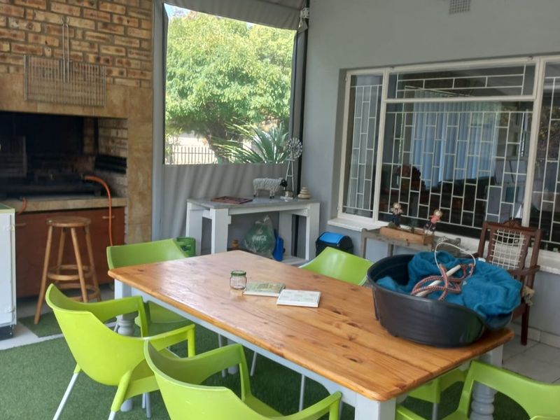 Covered patio area featuring a built-in brick braai, ceiling fan, and protective security bars on windows, suitable for outdoor entertaining.