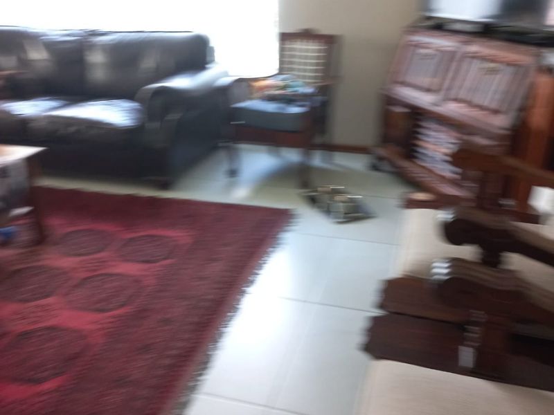 A living room area featuring tiled flooring and natural light from a large window.