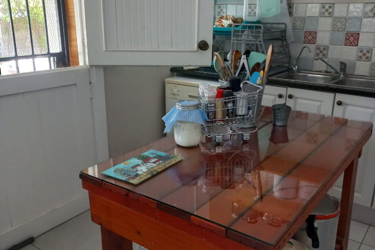 A functional kitchen area featuring tiled flooring, a stainless steel sink, decorative backsplash tiling, and open shelving for storage.