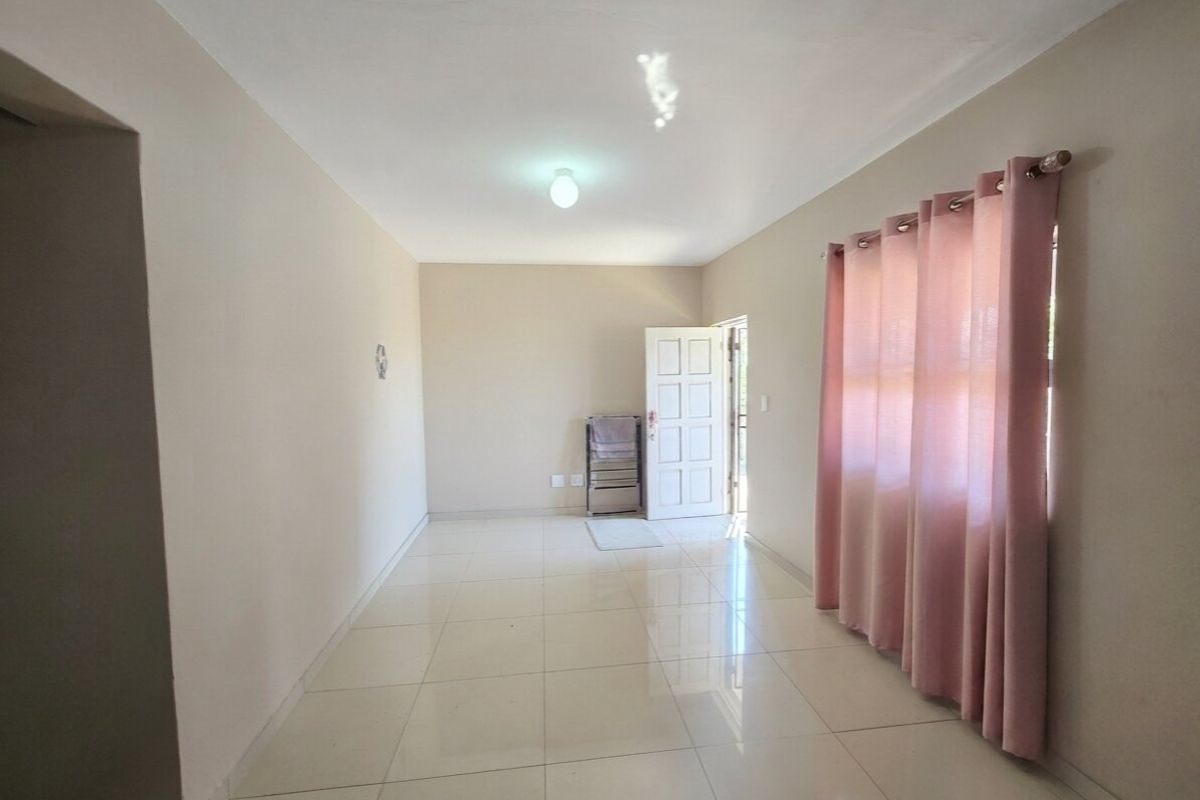 A bright, empty living room featuring neutral wall tones, polished tiled flooring, and a direct entrance door, offering a clean canvas for personalization.