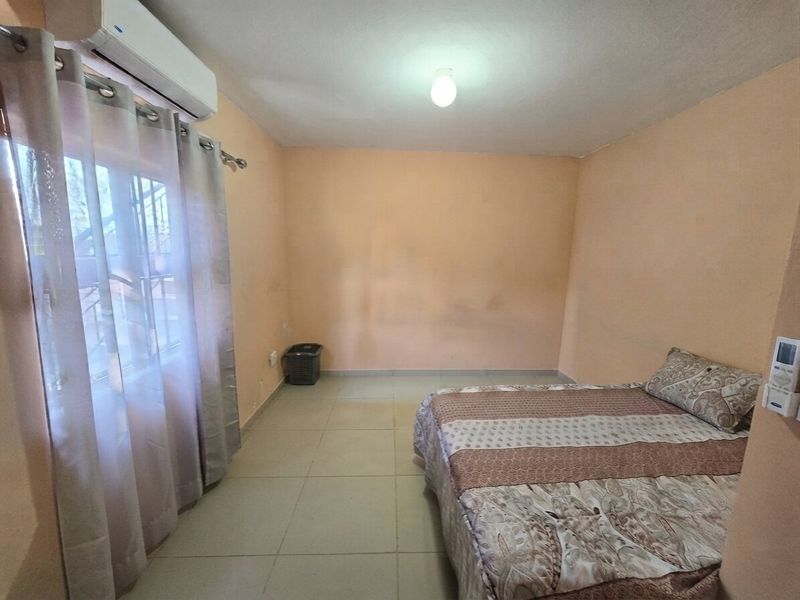 A bedroom featuring tiled flooring and a wall-mounted split-system air conditioner unit.