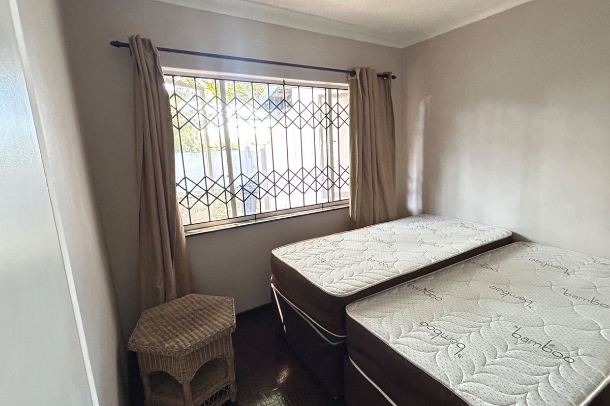 A bedroom featuring a window with a security gate and built-in cupboard space.
