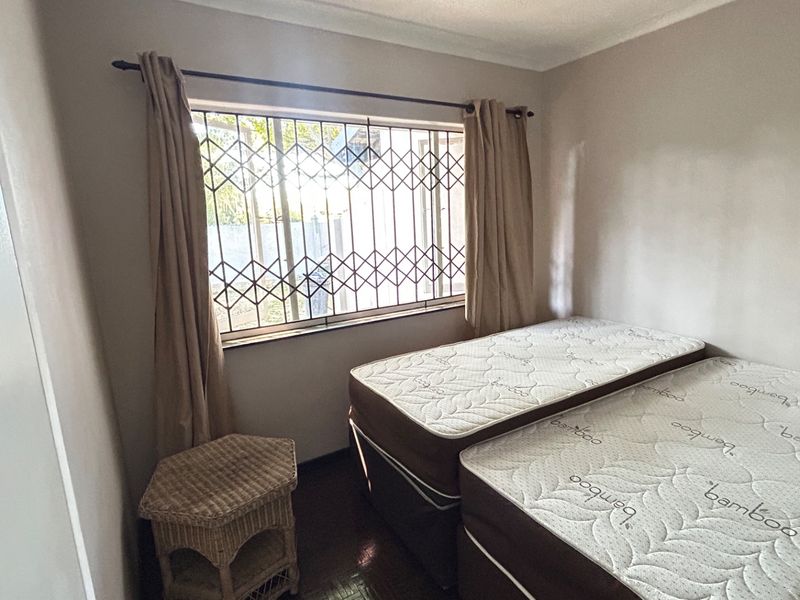 A bedroom featuring a window with a security gate and built-in cupboard space.