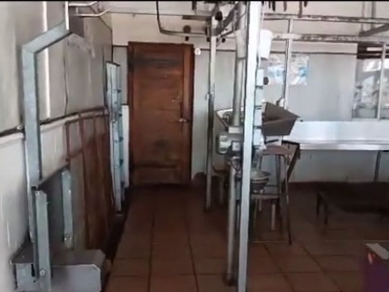 Industrial utility or processing area featuring overhead rail systems, tiled flooring, and stainless steel work surfaces, suitable for commercial operations.
