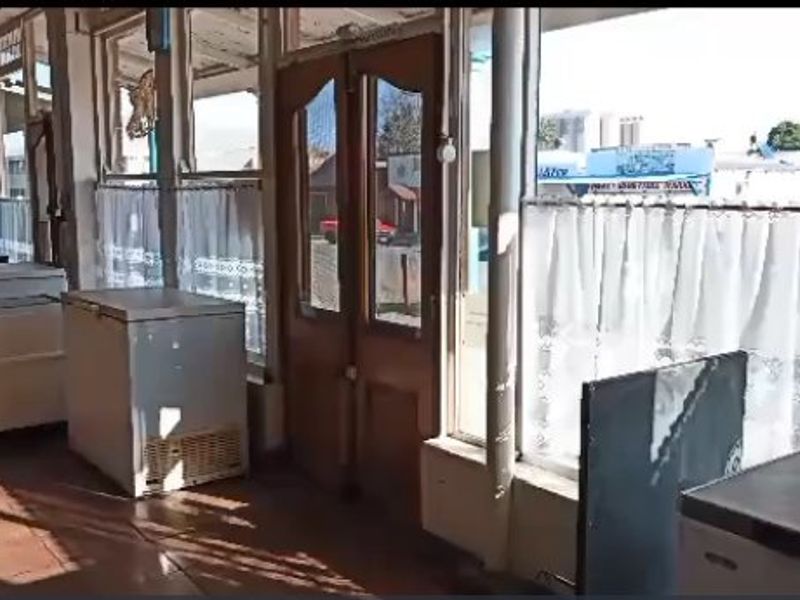 Commercial entry area featuring large glass storefront windows, double wooden doors, and tiled flooring, offering high visibility for potential customers.