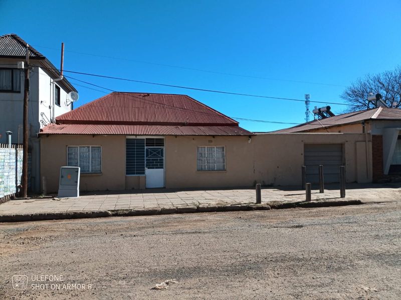 Front exterior view of a commercial property featuring a corrugated metal roof, security gates, and a small garage door.