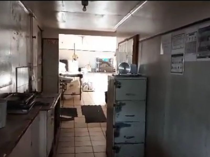 A functional commercial kitchen space featuring tiled flooring and built-in cabinetry, currently showing significant signs of wear and requiring refurbishment.