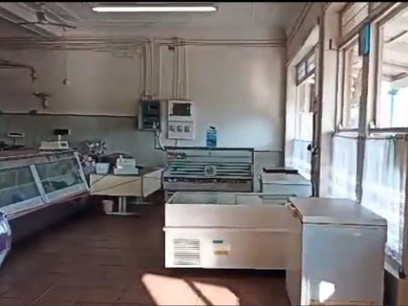 Commercial retail space featuring tiled flooring, large display windows, and multiple built-in refrigeration units, suitable for a butcher shop or food retail business.