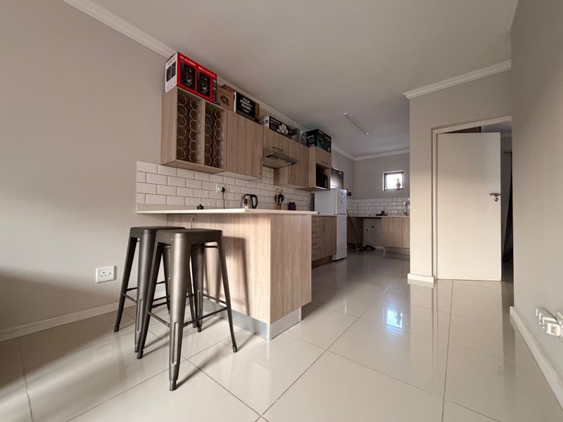 Modern open-plan kitchen featuring light wood cabinetry, subway tile backsplash, and a breakfast bar, seamlessly integrated with the living area.