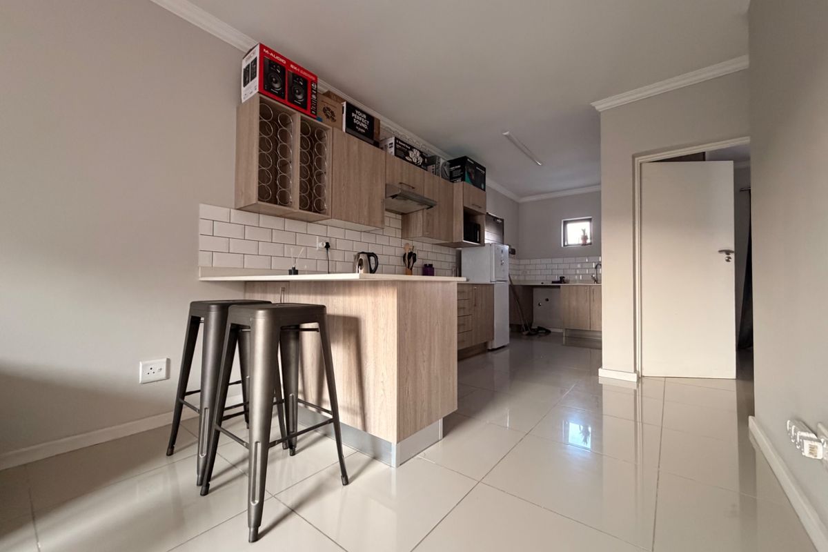 Modern kitchen featuring light wood cabinetry, subway tile backsplash, and a functional breakfast bar with tiled flooring throughout.