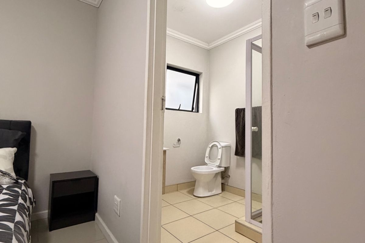 An en-suite bathroom featuring tiled flooring, a shower enclosure, and a toilet, accessible directly from the bedroom.
