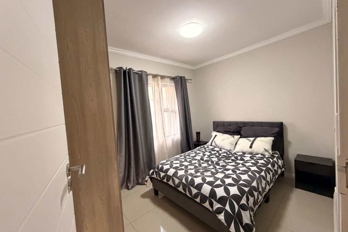 A well-maintained bedroom featuring neutral wall tones, tiled flooring, and decorative ceiling cornicing, providing a clean and comfortable living space.