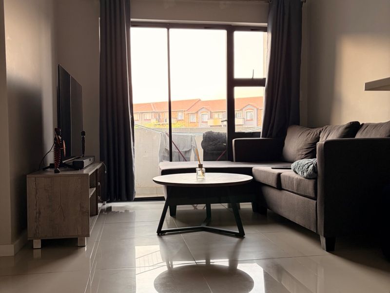A well-lit living room featuring polished tiled flooring, a coved ceiling, and a large sliding glass door providing access to the exterior.