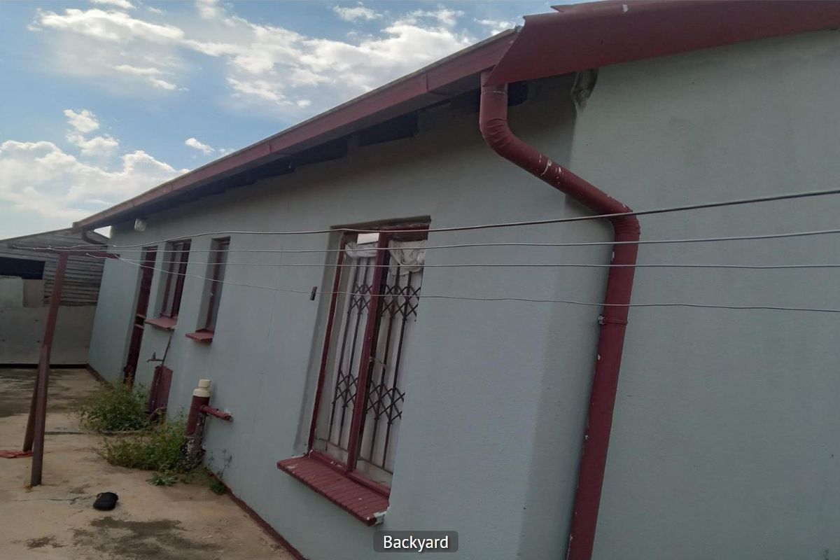 Rear exterior view of the property showing the back wall, guttering system, and security bars on the windows.