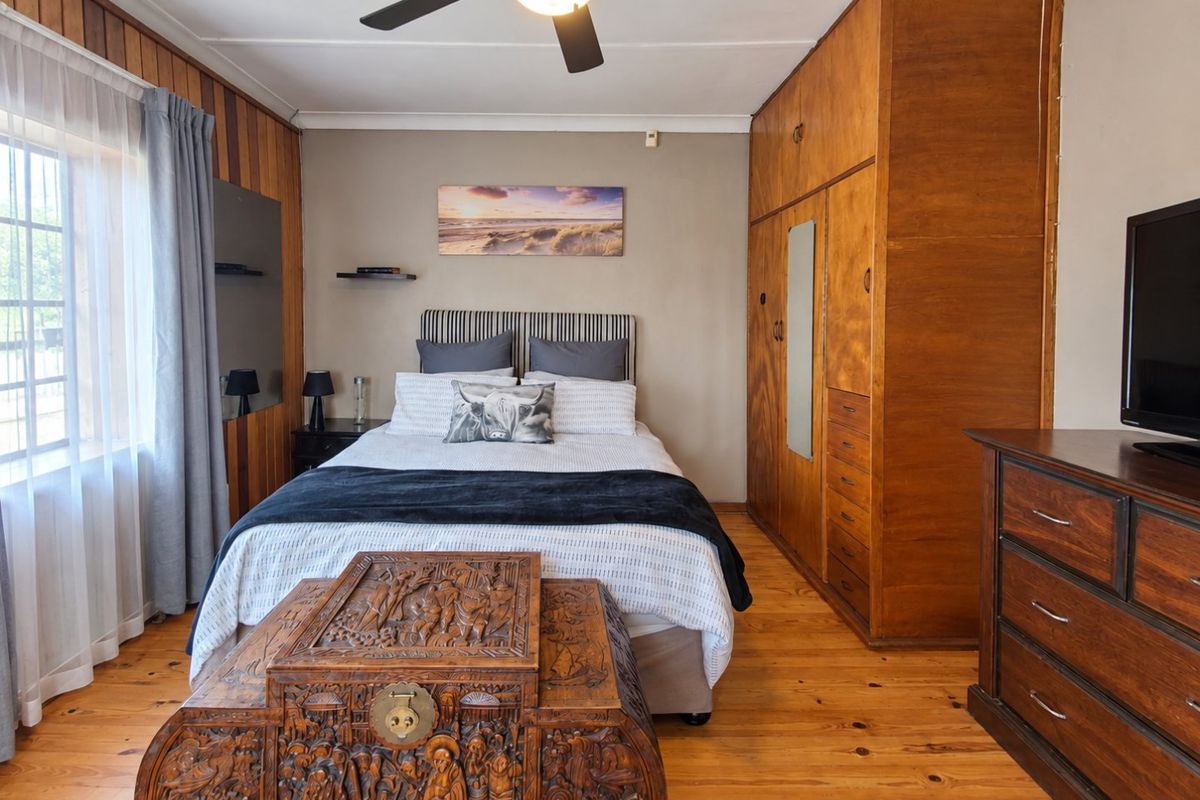 A bedroom featuring warm wood paneling, polished wooden floors, and a large built-in wooden wardrobe, offering a classic and cozy aesthetic.
