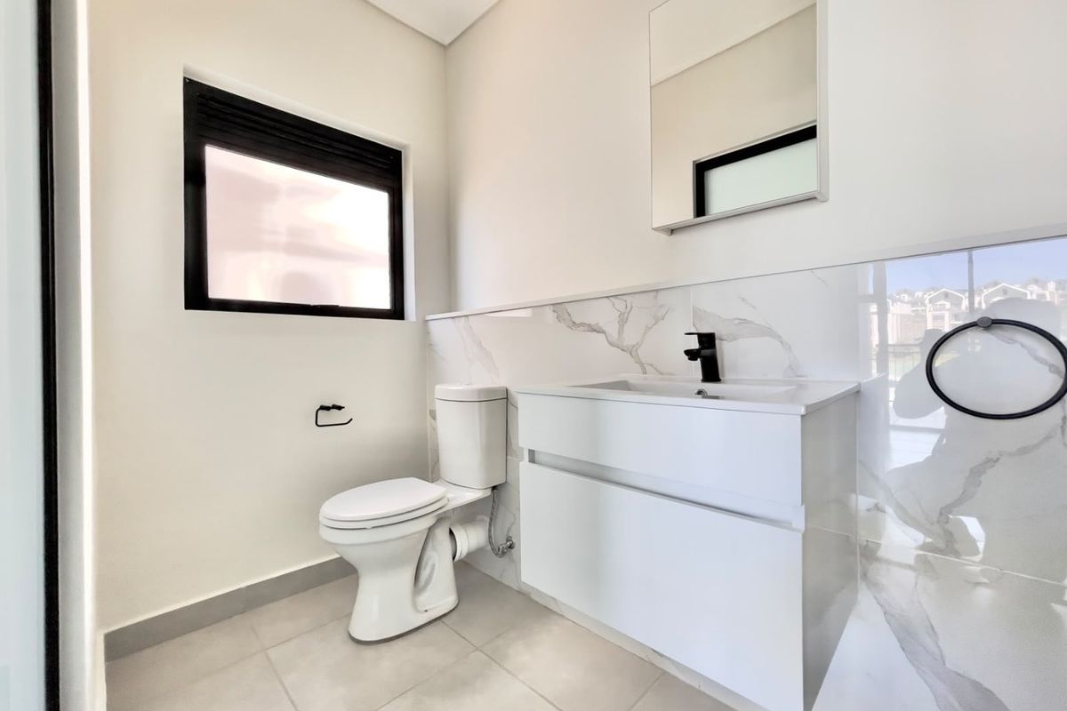 Modern bathroom featuring a wall-mounted vanity with a black mixer tap, marble-look wall tiles, and a clean, contemporary aesthetic.