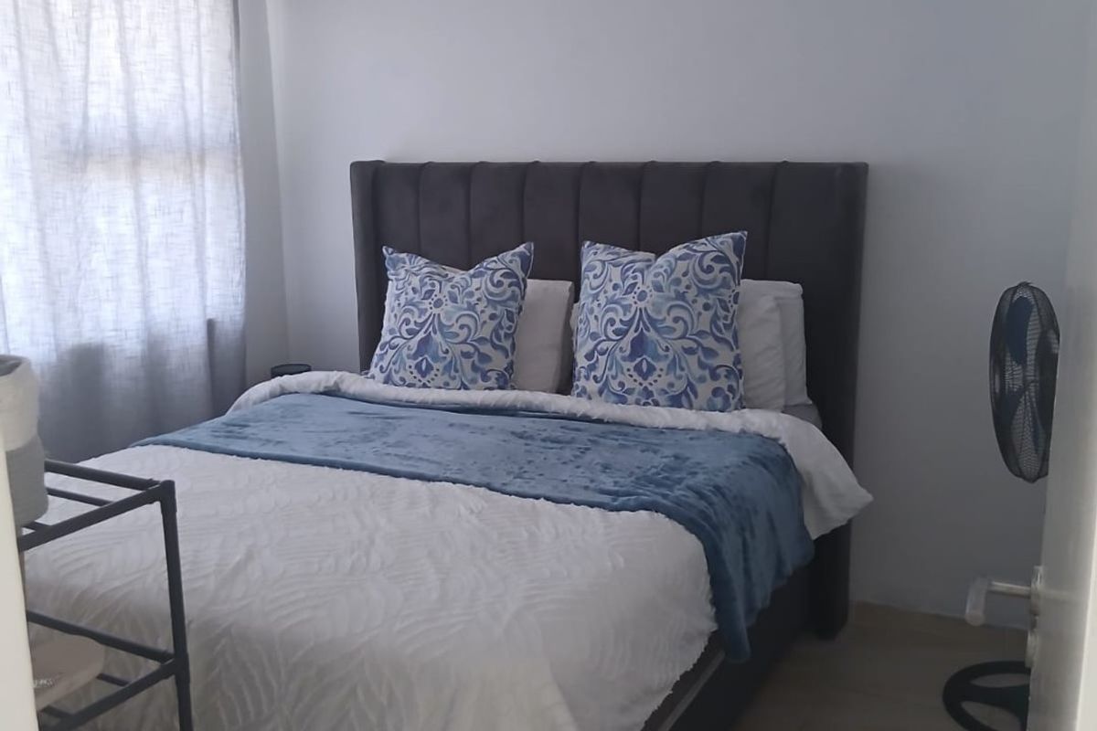 A functional bedroom featuring tiled flooring and a window with curtain rails, providing a neutral space ready for personalization.