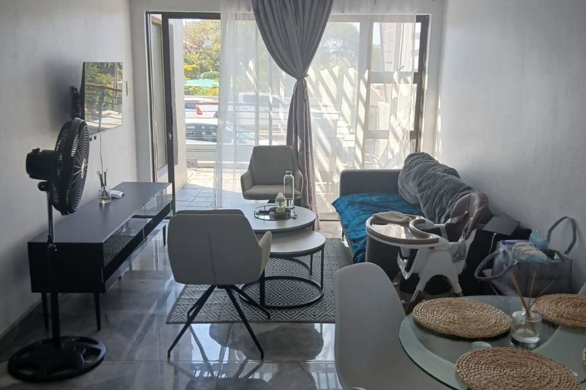 A living room area featuring large format floor tiles and a sliding glass door providing access to an outdoor space.