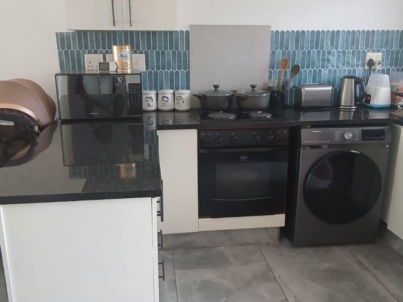 A functional kitchen featuring granite countertops, a tiled backsplash, built-in oven with hob, and integrated cabinetry with tiled flooring.
