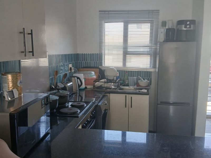 Compact kitchen featuring granite countertops, built-in cabinetry, a tiled backsplash, and integrated cooking appliances, offering a functional workspace.