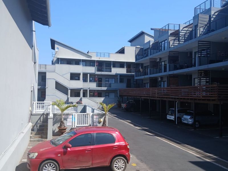 Exterior view of an apartment complex featuring multi-level residential units, open parking bays, and external staircases.