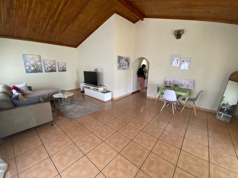 Spacious open-plan living and dining area featuring a high vaulted timber ceiling and durable ceramic floor tiles.