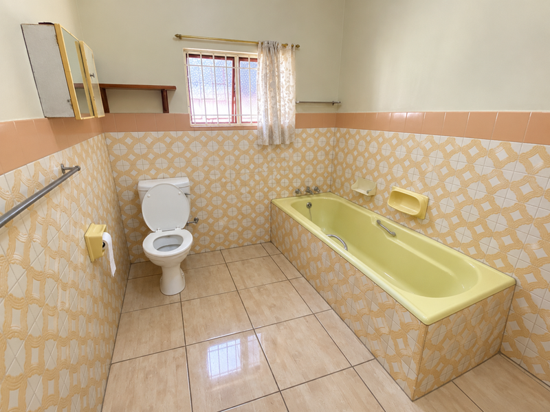 A functional bathroom featuring a built-in bathtub, toilet, and classic tiled finishes, offering a clean space with potential for modern updates.