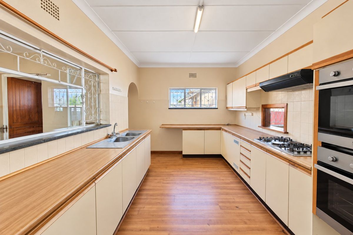 A spacious, empty kitchen featuring laminate countertops, built-in oven, gas cooktop, and ample cabinetry, offering a functional layout ready for modernization.