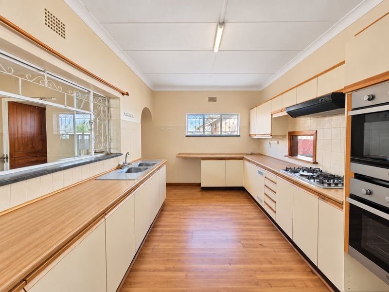 A spacious, empty kitchen featuring laminate countertops, built-in oven, gas cooktop, and ample cabinetry, offering a functional layout ready for modernization.