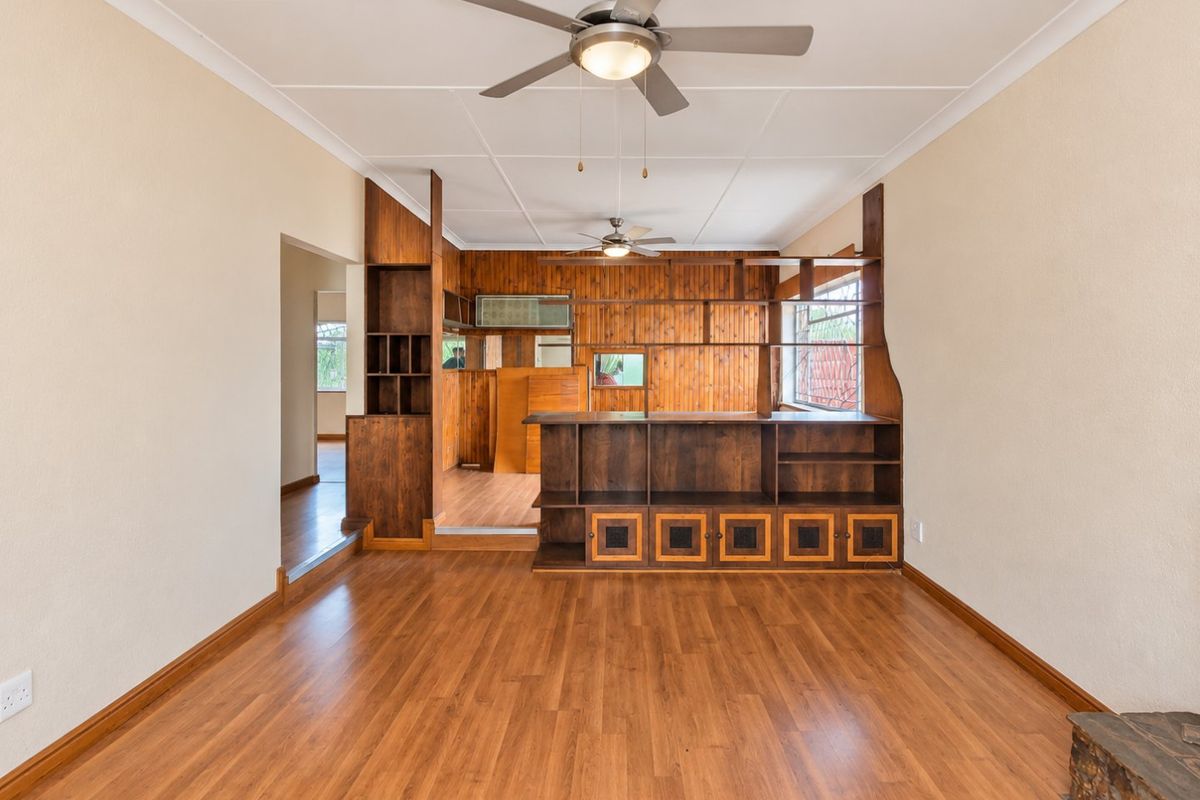 Spacious living area featuring laminate flooring, dual ceiling fans, and extensive built-in wooden cabinetry and shelving units.