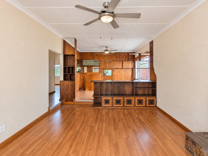 Spacious living area featuring laminate flooring, dual ceiling fans, and extensive built-in wooden cabinetry and shelving units.