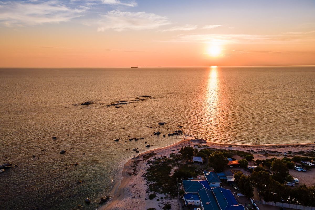 Aerial view of the coastal property at sunset, showcasing direct beach access and proximity to the ocean.
