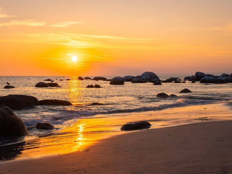 A scenic sunset view over the ocean and rocky coastline, highlighting the natural beauty and tranquil atmosphere of the property's surroundings.