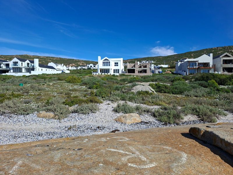 A scenic view of a coastal residential estate featuring established homes and ongoing construction set against a natural landscape.