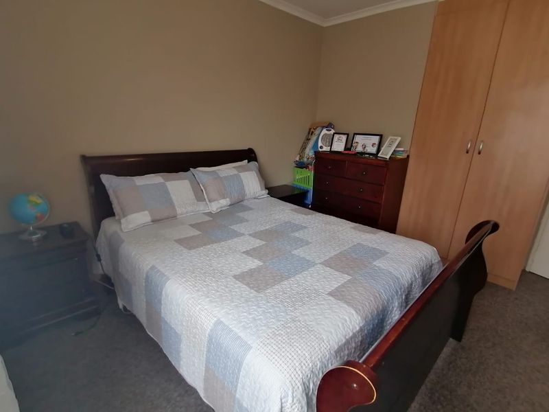 A standard bedroom featuring neutral wall tones and a built-in wooden wardrobe, providing functional storage space.