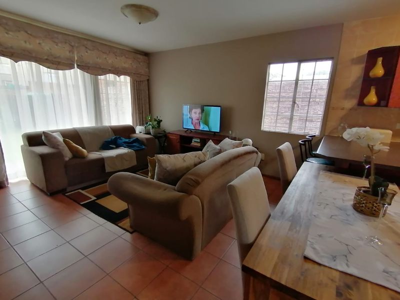 Open-plan living and dining area featuring tiled flooring and large windows, providing a functional and connected space for daily living.
