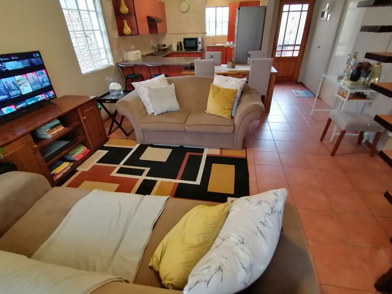 Open-plan living and kitchen area featuring tiled flooring, a breakfast bar, and direct access to the entrance.