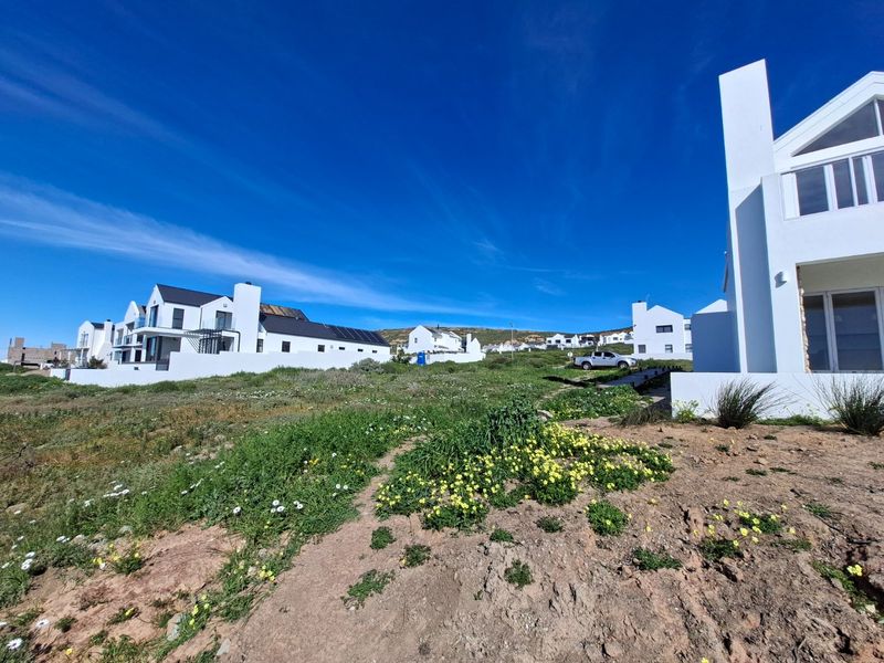 A view of the rear exterior of a modern white residential property with solar panels, set within a coastal landscape.