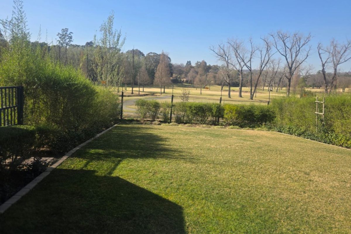 A well-maintained private garden featuring a manicured lawn, perimeter fencing, and established hedging, offering scenic views of the surrounding landscape.