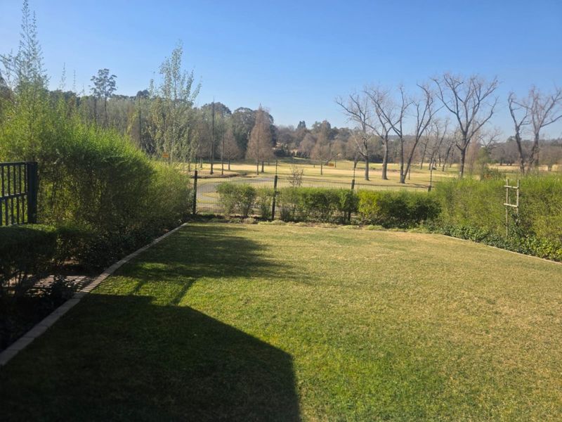 A well-maintained private garden featuring a manicured lawn, perimeter fencing, and established hedging, offering scenic views of the surrounding landscape.