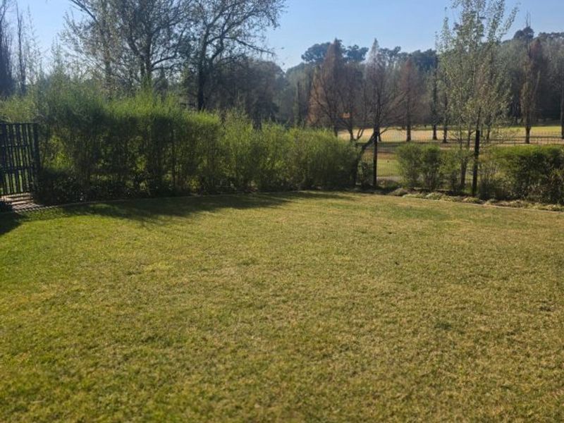 A well-maintained private garden area featuring a manicured lawn and established perimeter hedging with views of the surrounding landscape.